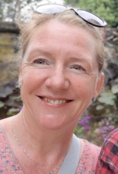 A professional portrait of Jane Ford, reflexologist, smiling warmly, reflecting her friendly and welcoming approach to holistic healing.