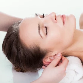 Close-up view of reflexology being performed on a client's ears, illustrating the versatility of reflexology in targeting different areas of the body.